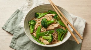 Un bol de nouilles de konjac translucides sautées avec des légumes verts et des baguettes